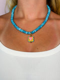 Blue beaded necklace with yellow/pink heart charm